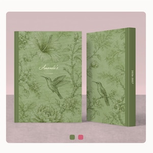 Puede incluir: Una agenda de color verde salvia con un estampado botánico verde oscuro de flores de hibisco y colibríes. La portada muestra el texto Amanda's PLANNER en blanco. El lomo indica los años 2026-2027 impresos en color blanco.