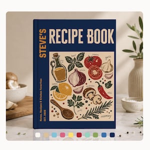 Puede incluir: Un libro de recetas de tapa dura azul oscuro titulado STEVE'S RECIPE BOOK. La portada presenta una ilustración central sobre un fondo beige que representa ingredientes como aceite de oliva, albahaca, tomates, ajo, cebolla, limón, champiñones, chile, perejil y romero.
