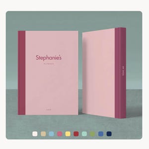 Op de afbeelding: Twee roze planners met bordeauxrode ruggen en accenten. De voorste planner heeft de tekst "Stephanie's Planner" en "2026". De rug van de tweede planner heeft de tekst "MY 2026". De achtergrond is een gedempt teal.