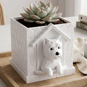 May include: A white square planter featuring a sculpted dog house design with a West Highland White Terrier figure peeking out from the front. The exterior walls have a repeating heart pattern, and the planter contains a green succulent plant.