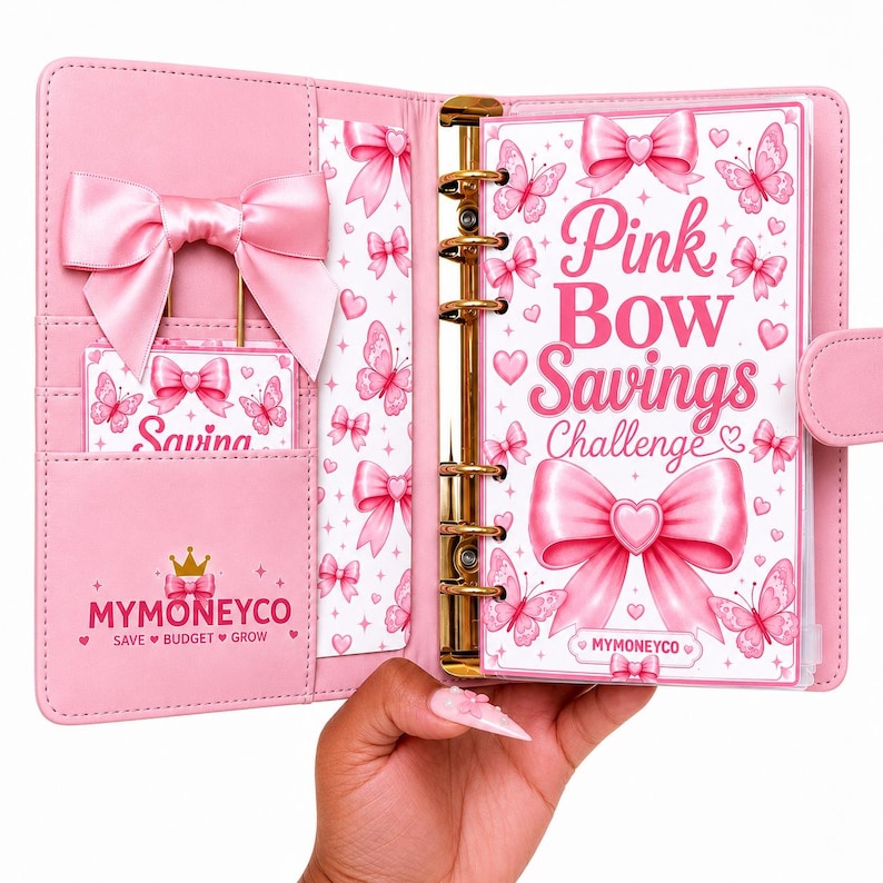 Pu&ograve; includere: Un raccoglitore rosa a sei anelli con un grande fiocco in raso sulla copertina sinistra e un inserto per la sfida di risparmio sulla destra. L'inserto mostra il testo Pink Bow Savings Challenge con grafiche di farfalle e fiocchi. Il marchio MYMONEYCO &egrave; visibile.