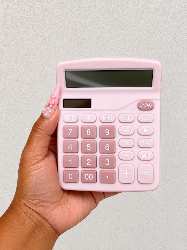 Pu&ograve; includere: Una calcolatrice da tavolo rosa chiaro con uno schermo rettangolare e una griglia di pulsanti quadrati. I tasti numerici sono rosa chiaro, mentre i tasti funzione sono di una tonalit&agrave; di rosa leggermente pi&ugrave; scura, disposti in layout.