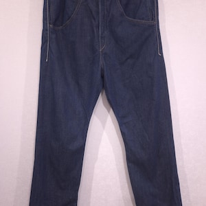May include: A pair of dark blue denim jeans featuring a high-waisted design with a button fly closure, two deep front pockets with visible white stitching along the edges, and a straight-leg cut with a classic five-pocket construction style.