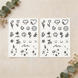 Könnte beinhalten: Zwei Bögen temporärer Tattoos mit schwarzen Strichzeichnungen. Die Designs umfassen Blumen, Herzen, Smiley-Gesichter, Schmetterlinge, Palmen, Kirschen, Noten, Planeten, Sterne und Wellen.