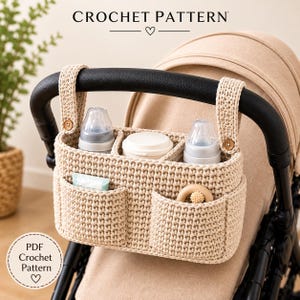 Könnte beinhalten: Ein beigefarbener Kinderwagen-Organizer aus Häkelarbeit mit mehreren Fächern, zwei kleinen Holzknöpfen an den Riemen und dem Text CROCHET PATTERN. Er enthält zwei Babyflaschen, einen weißen Behälter, eine kleine Tube und einen Holzring.