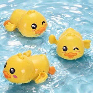 May include: Three yellow toy ducks floating in blue water. Each duck has a smiling face with black eyes, an orange beak, and orange feet. The ducks are designed for bath time or water play.