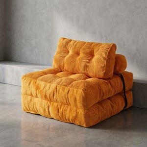 May include: A mustard-yellow corduroy modular sofa with a buttoned design. The sofa comprises three stacked cushions and a backrest, all in a solid colour. A black strap secures the cushions together.