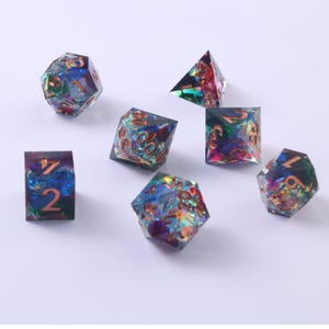 May include: A set of seven polyhedral dice made of translucent resin with embedded iridescent foil flakes in shades of blue, purple, and green. Each die features engraved numbers filled with a metallic copper-colored pigment for visibility.