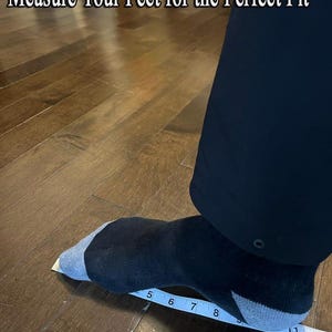 K&ouml;nnte beinhalten: Ein Fu&szlig; in einer schwarz-grauen Socke auf einem wei&szlig;en Ma&szlig;band, das Ma&szlig;e in Zoll anzeigt. Der Text "Measure Your Feet for the Perfect Fit" ist oben im Bild zu sehen und weist auf eine Gr&ouml;&szlig;entabelle hin.