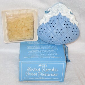 May include: An Avon Sweet Cherubs Closet Pomander set. The set includes a light blue purse-shaped pomander with cherub accents, a box, and a small container of potpourri. The box reads "Sweet Cherubs Closet Pomander".