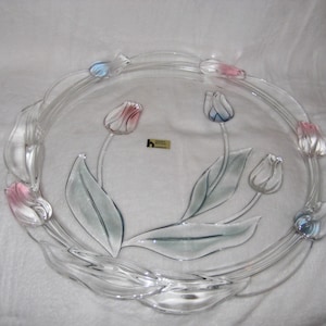 May include: Clear glass serving plate with a floral tulip design. The plate features pink and blue tulips with green leaves. The rim of the plate has a decorative, wavy design.