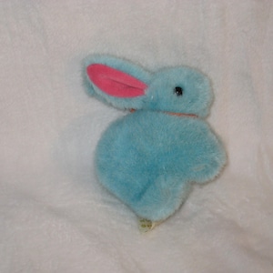May include: A plush blue bunny with pink inner ears and a small black eye. The stuffed animal is made of soft, fuzzy material and has a small tag attached to its foot. The bunny is a cute and cuddly toy.