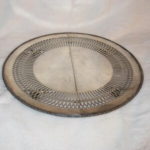 May include: Oval silver serving tray with a pierced, openwork design in the centre. The tray has a decorative beaded edge. The tray is likely made of metal and is suitable for serving food or displaying decorative items.