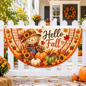 May include: A semi-circular fan-shaped banner featuring a scarecrow, pumpkins, sunflowers, and autumn leaves. The text "Hello Fall" is printed in a dark brown script font. The banner has metal grommets and is displayed on a white picket fence.