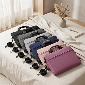 May include: A collection of six rectangular laptop sleeves arranged in a diagonal row. The sleeves feature top handles, zippered closures, and detachable shoulder strap clips. The colours include black, dark grey, light grey, navy blue, light pink, and purple.