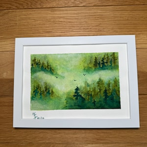 Könnte beinhalten: Aquarellmalerei einer Waldszene in einem weißen Rahmen. Das Kunstwerk zeigt grüne und gelbe Bäume mit einem nebligen Hintergrund und drei Vögeln im Flug. Unten links signiert mit dem Datum 02/26.