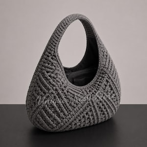 May include: A dark gray hobo-style handbag featuring a textured, geometric crochet pattern. The bag has a single integrated handle and an open top revealing a dark interior lining with a zippered pocket. The text Unique Nest Store is visible.
