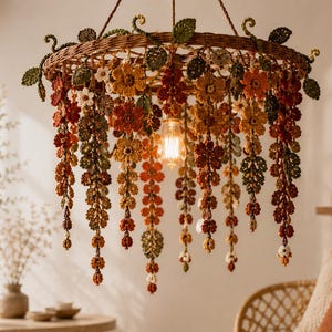 May include: A circular chandelier featuring a woven brown frame adorned with crocheted flowers and leaves in shades of orange, red, yellow, and green. Multiple strands of floral crochet hang downward, surrounding a single exposed Edison light bulb.