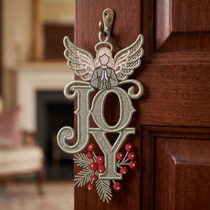 May include: An embroidered hanging ornament featuring the word JOY in light sage green thread. Above the letters is a stylized angel with lace-like wings and a halo. Below, red berries and pine needles are stitched onto the letter Y.