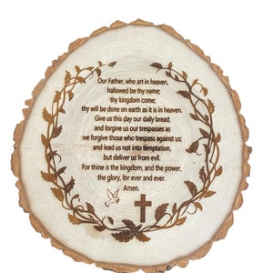 May include: A wooden slice with a laser-engraved design of a vine wreath and the Lord's Prayer. The text reads: "Our Father, who art in heaven, hallowed be thy name; thy kingdom come; thy will be done on earth as it is in heaven. Give us this day our daily bread; and forgive us our trespasses as we forgive those who trespass against us; and lead us not into temptation, but deliver us from evil. For thine is the kingdom, and the power, the glory, for ever and ever. Amen."