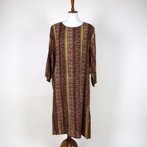 May include: A long-sleeved dress with a snake print design. The dress features vertical stripes in shades of brown, gold, and red. The dress is displayed on a wooden mannequin.