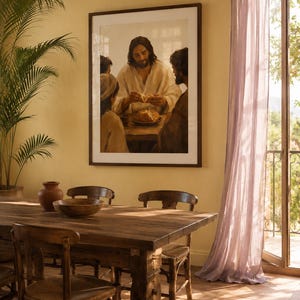 May include: A framed print depicting a religious scene of people gathered around a table. The print is displayed on a yellow wall above a wooden dining table with chairs. A large plant and sheer purple curtains are also visible.