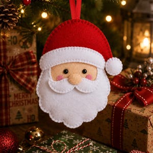 May include: A felt Santa Claus ornament featuring a red hat with a white pom-pom, a beige face with black eyes, pink cheeks, and a white beard. The ornament is suspended by a red ribbon loop and displays visible white stitching along the edges.