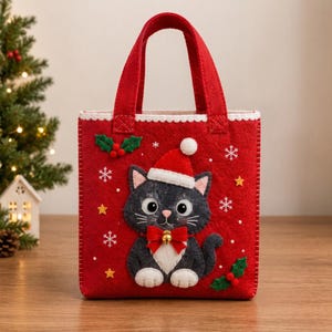 Pode incluir: Uma bolsa de feltro vermelha com um gato cinza-escuro usando um gorro de Papai Noel e um laço vermelho com um pequeno sino dourado. A bolsa é decorada com flocos de neve de feltro branco, estrelas amarelas e folhas de azevinho verdes.