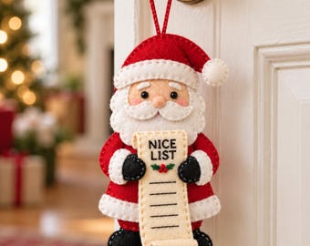 May include: A felt Santa Claus ornament featuring a red and white suit, a matching hat with a pom-pom, and black boots. Santa holds a cream-colored scroll with the text NICE LIST and a small embroidered holly sprig with red berries.