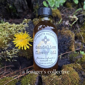 May include: A bottle of dandelion flower oil with a black cap and a white label. The label reads "dandelion flower oil" and "flowers infused in avocado oil." A yellow dandelion flower is next to the bottle. The text "a forager's collective" is also visible.