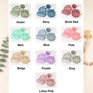 May include: A collection of baby feeding sets in various colors, including green, navy, brick red, mint, blue, pink, beige, purple, gray, and lotus pink. Each set includes a bib, bowl, plate, spoon, and fork.