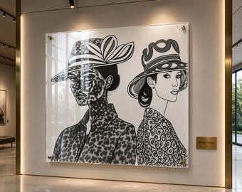Könnte beinhalten: Ein großes, gerahmtes Kunstwerk mit zwei Frauen mit Hüten, in Schwarz-Weiß dargestellt. Eine Frau hat ein gemustertes Gesicht und eine Jacke, die andere eine gemusterte Bluse. Das Kunstwerk ist an einer hellen Wand befestigt.