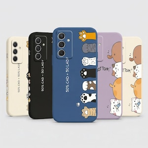 May include: A collection of five phone cases with unique designs. The cases feature various colors, including cream, black, blue, lavender, and beige. Each case has a different design, such as cat paws, cat faces, and the text "50% CAD + 50 LADY".