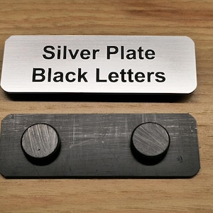 May include: A silver plate with the text "Silver Plate Black Letters" engraved on it. The plate is attached to a black magnetic strip with two round magnets.