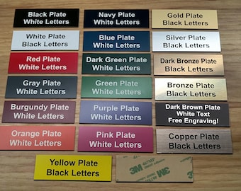 May include: A collection of rectangular name plates in various colors including black, navy, gold, white, blue, silver, red, dark green, dark bronze, gray, green, bronze, burgundy, purple, dark brown, orange, pink, copper, and yellow with text.