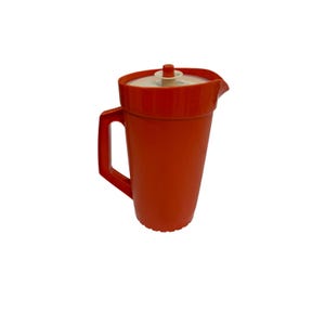 May include: A bright orange plastic pitcher featuring a sturdy side handle and a matching orange lid with a small, centered beige knob. The pitcher has a tapered cylindrical body and a molded pouring spout at the top rim for liquid dispensing.