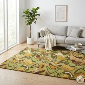 May include: A green mid-century modern area rug with a repeating pattern of brown, yellow, and white boomerang shapes and starbursts. The rug is placed in a living room with a gray sofa and a fiddle-leaf fig plant.