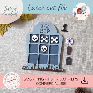 May include: A tombstone-shaped tic-tac-toe game board in light blue with the text TIC-TAC RIP. The board features a grid with white skull and bone game pieces. Additional game pieces include a black hand, a bloodshot eyeball, a coffin, and a tombstone.