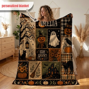 May include: A rectangular throw blanket featuring a patchwork design with Halloween motifs including a ghost, a black cat, a jack-o'-lantern, a haunted house, and a broomstick. The text AMELIA and STAY SPOOKY is printed on the blanket.