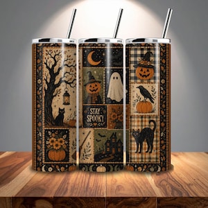 May include: A cylindrical tumbler with a metal straw featuring a Halloween-themed patchwork design. The print includes a black cat, a ghost, a jack-o'-lantern wearing a witch hat, a crow, a haunted house, and the text STAY SPOOKY in orange and black.