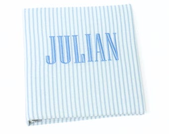 May include: A blue and white striped fabric baby blanket with the name "JULIAN" embroidered in blue thread.