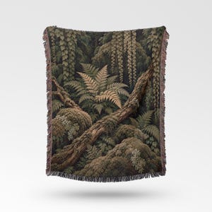 May include: A woven throw blanket featuring a detailed forest scene with moss-covered logs, lush green ferns, and hanging vines. The rectangular textile has a fringed edge and displays a dark, earthy color palette of deep greens and browns.