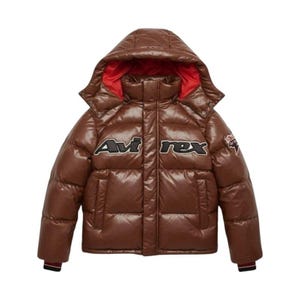 May include: A brown puffer jacket with a hood and red lining. The jacket features the text "Avirex" in black and white on the front. A small patch is visible on the right sleeve. The jacket has a glossy finish and a sporty design.