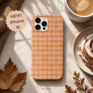 Op de afbeelding: Een telefoonhoesje voor de iPhone 18 met een lichtoranje en zachtroze ruitpatroon in aquarel-stijl. Het hoesje heeft een uitsparing voor een drievoudig camerasysteem. Een rond label toont de tekst NEW! iPhone 18 in zwarte letters.