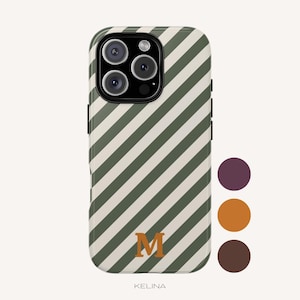 Op de afbeelding: Een smartphonehoesje met een diagonaal streeppatroon in olijfgroen en crème. Het hoesje toont een opvallende oranje letter M in het midden onderaan. Rechts zijn drie cirkelvormige kleurstaaltjes in pruim, oranje en bruin zichtbaar.