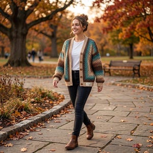May include: A woman wearing a button-up cardigan with a geometric pattern in shades of brown, teal, and beige. The cardigan is paired with a white t-shirt, black jeans, and brown boots. The scene is set in a park with autumn foliage.