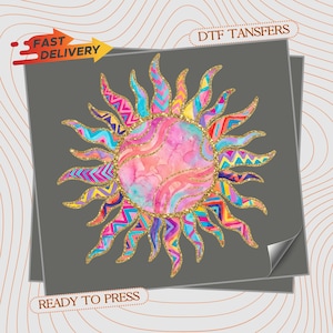 May include: A colorful sun design with a watercolor effect, featuring pink, blue, and yellow hues. The sun's rays are adorned with geometric patterns and gold glitter accents. The image includes the text "FAST DELIVERY", "DTF TRANSFERS", and "READY TO PRESS".
