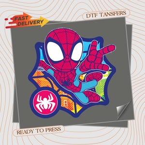 May include: A DTF transfer featuring a cartoon Spider-Man character in a red and blue suit with large white eyes, positioned in front of a stylized web. The design includes a circular white spider icon on a pink background and colorful geometric patterns.