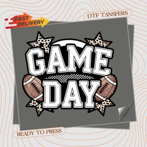 May include: A DTF transfer graphic featuring the text GAME DAY in bold white block letters with black outlines. The design includes two brown footballs, two leopard print stars, and the text FAST DELIVERY and READY TO PRESS on a gray background.