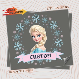 May include: A DTF transfer sheet featuring a cartoon illustration of a blonde character with a braid, wearing a blue dress, surrounded by a wreath of light blue and pink snowflakes. A pink banner across the bottom contains the text CUSTOM.